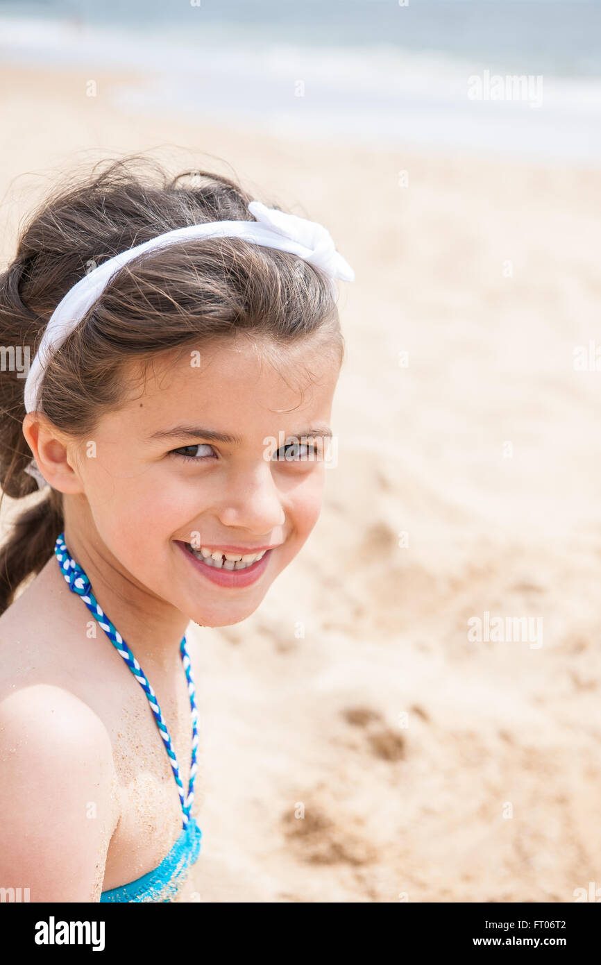 A smiling six year old is looking at the camera in swimsuit. Focus on