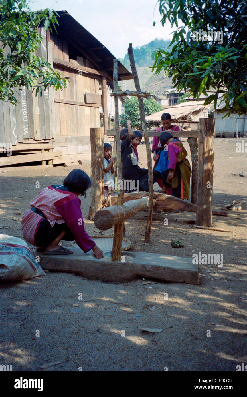 young girl pounding rice in a rural village in north thailand Stock Photo