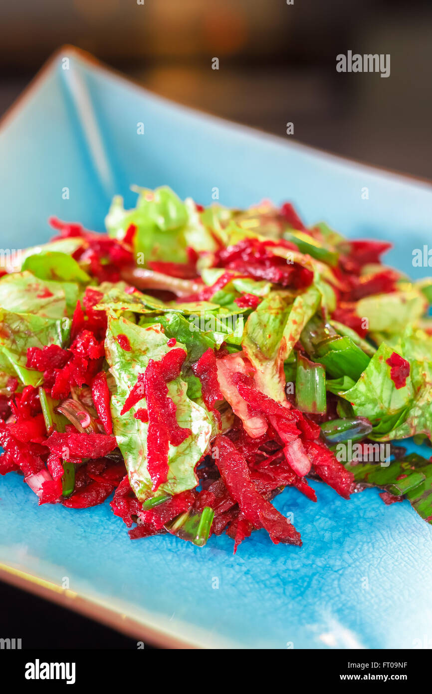Lettuce and beetroot salad served on blue plate with scallion, ramsons, lemon and olive oil Stock Photo