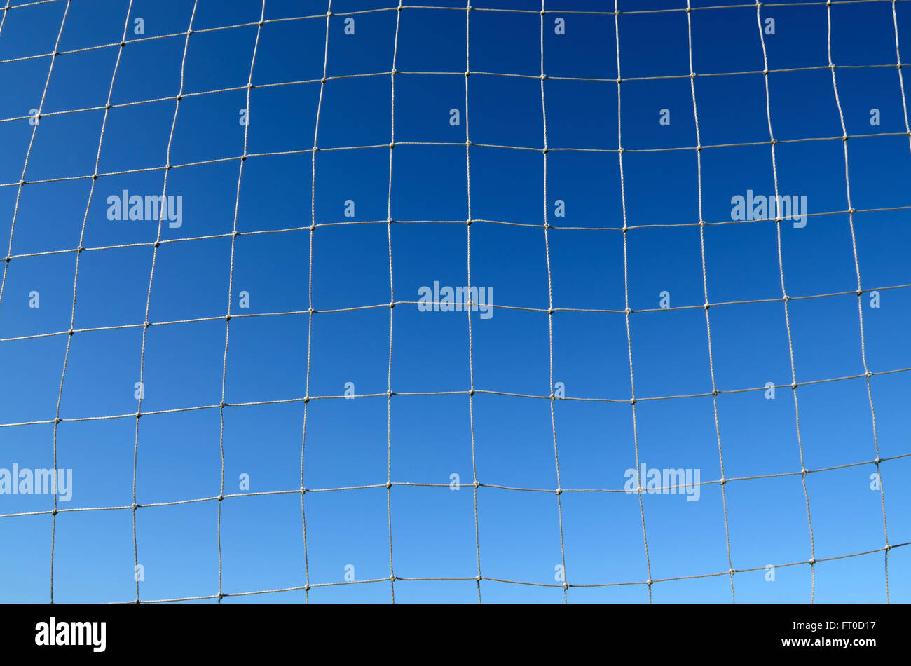 The Net of a Soccer Field against a Vivid Blue Sky background Stock Photo