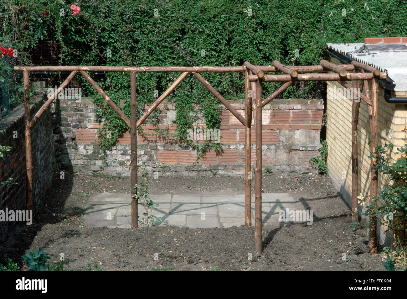 A newly made rustic wooden pergola in a garden undergoing renovation Stock Photo