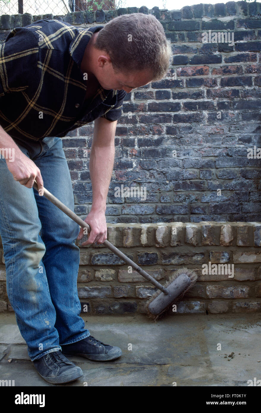 Man brushing a newly built low stone wall for a new raised bed         FOR EDITORIAL USE ONLY Stock Photo