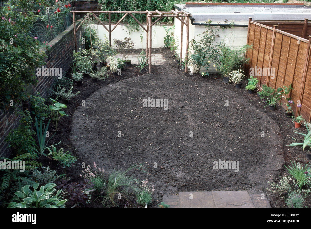 View of a circular lawn and rustic wooden pergola in newly renovated garden Stock Photo