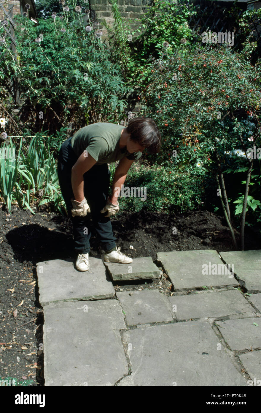 Woman replacing broken paving on patio   FOR EDITORIAL USE ONLY Stock Photo