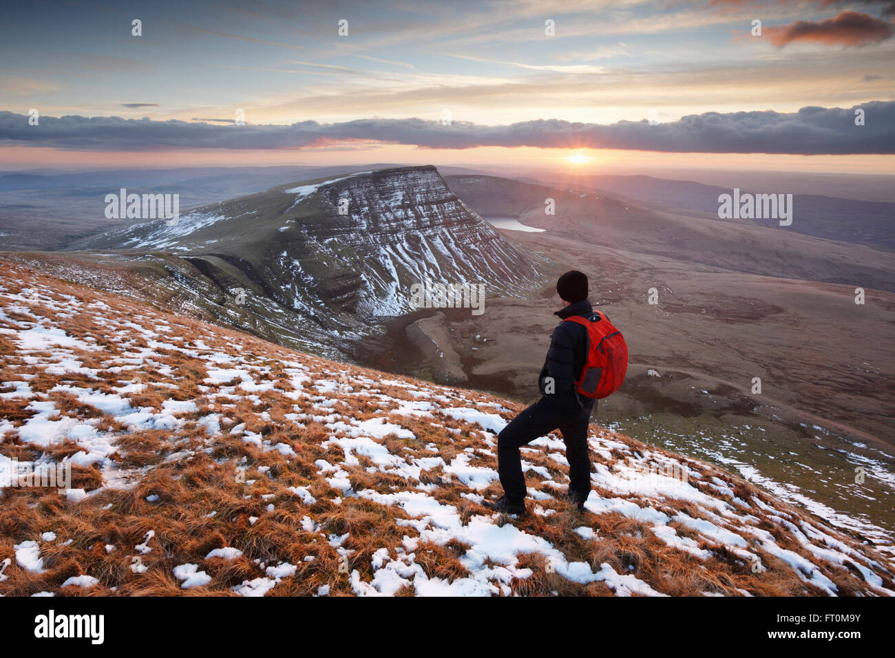 Hillwalker watching a winter sunset on The Black Mountain. Brecon Beacons National Park. Carmarthenshire. Wales. UK. Stock Photo