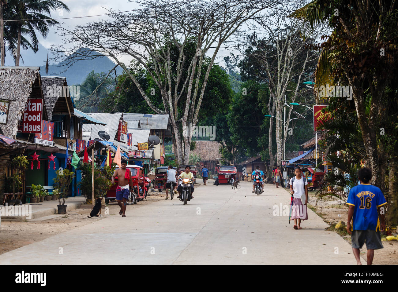 Village street scene on Leyte island, Philippines,  showing native stores and people walking and riding Stock Photo