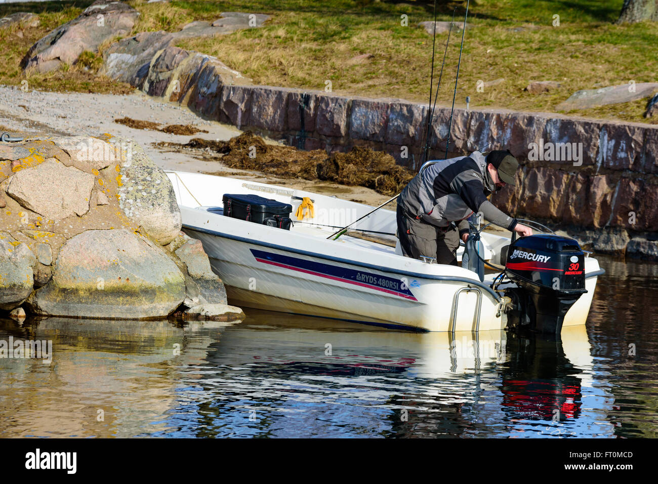 Torhamn, Sweden - March 18, 2016: One person stand in an open motorboat leaning over the motor and checking the gas level before Stock Photo
