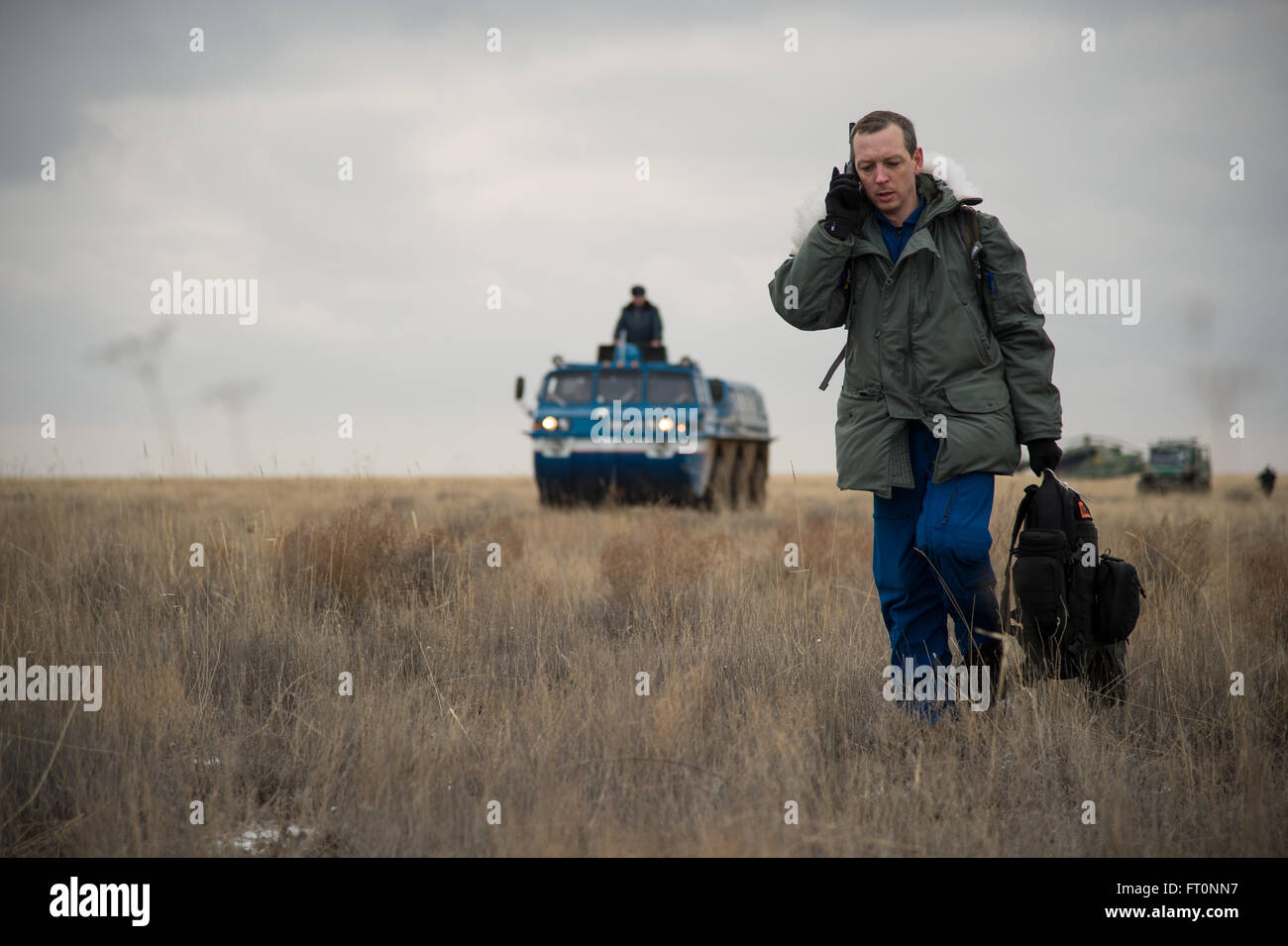 NASA Director for Human Space Flight Programs - Russia Sean Fuller talks on a satellite phone as an all terrain vehicle (ATV) brings Expedition 46 Commander Scott Kelly of NASA to a waiting helicopter at the soyuz landing site near the town of Zhezkazgan, Kazakhstan on Wednesday, March 2, 2016 (Kazakh time). Kelly and Russian cosmonaut Mikhail Kornienko completed an International Space Station record year-long mission to collect valuable data on the effect of long duration weightlessness on the human body that will be used to formulate a human mission to Mars. Russian cosmonaut Sergey Volkov r Stock Photo