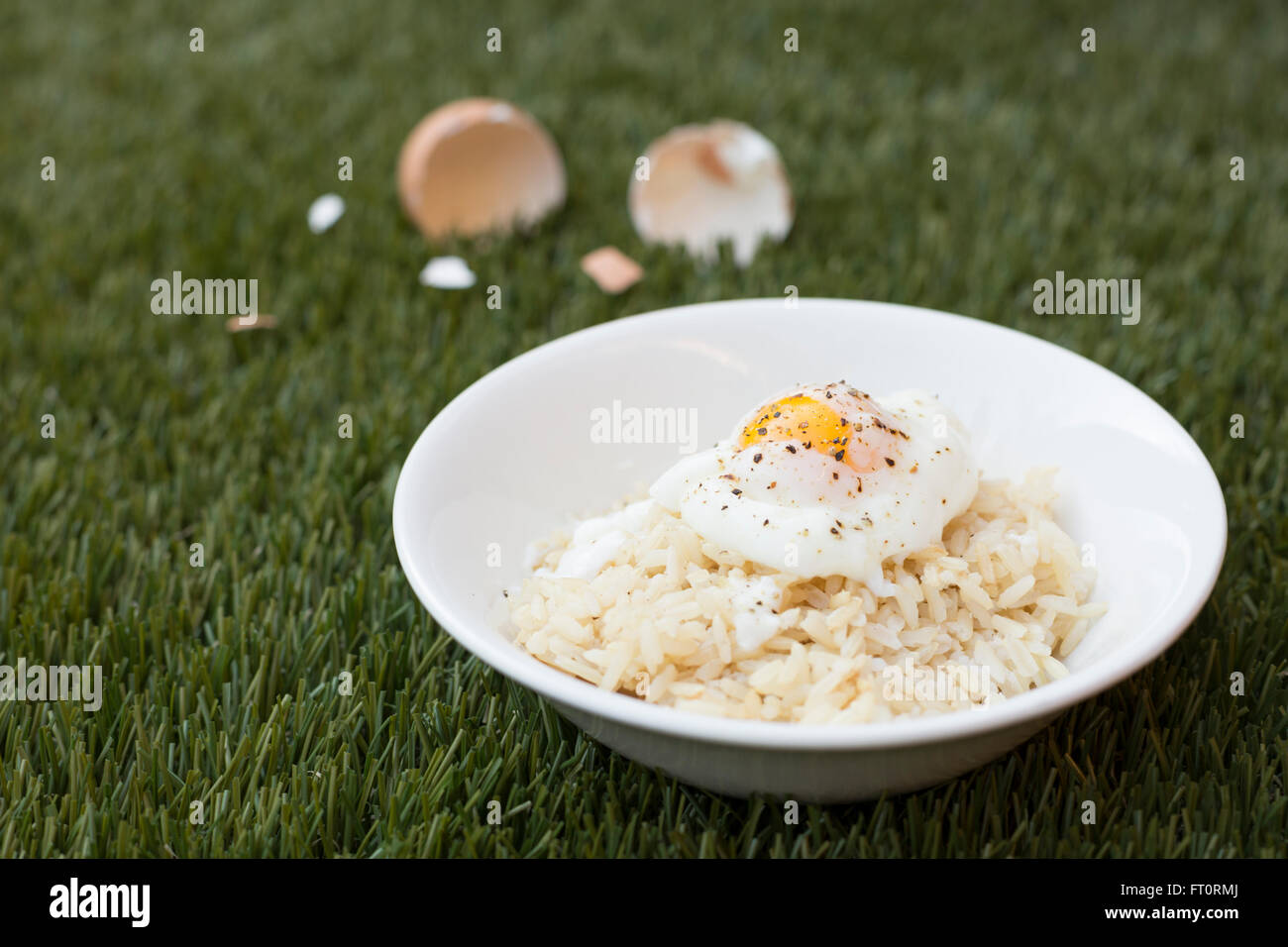 Japanese Soft Boiled Egg over Rice in White Bowl on Grass Stock Photo