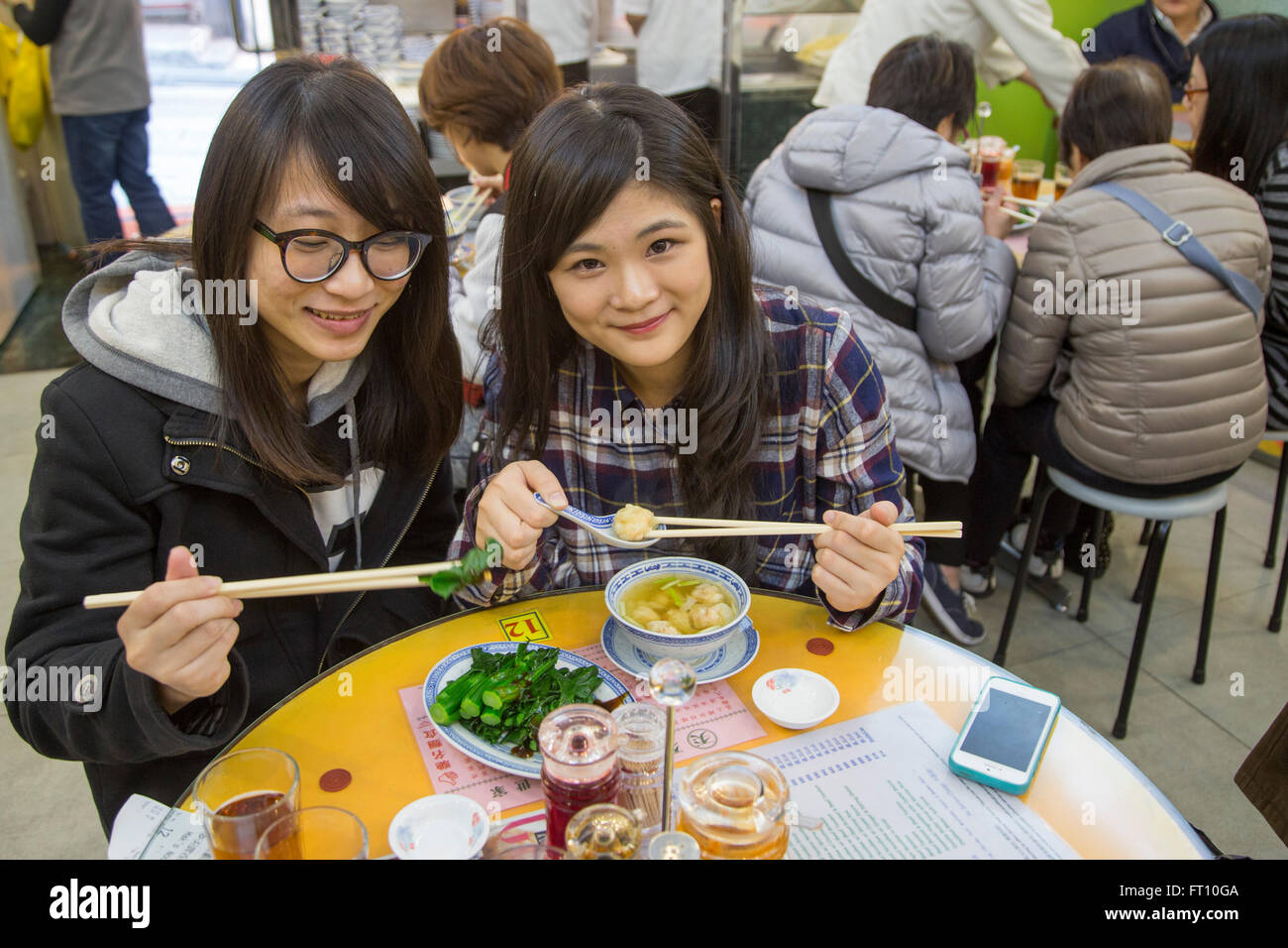 Two teenage girls enjoying lunch at Mak's Noodle Restaurant, Central, Hong Kong Island, Hong Kong Stock Photo