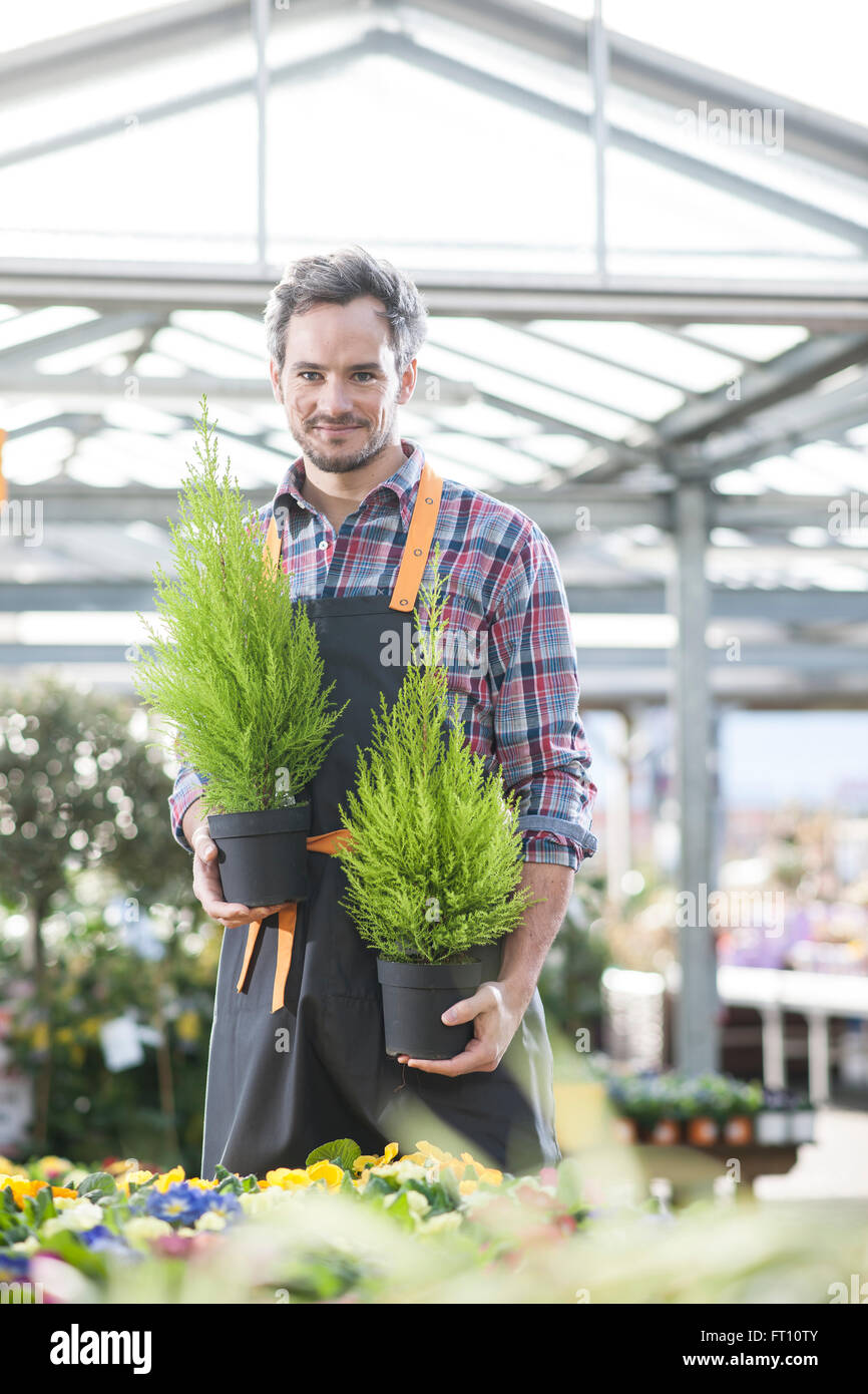 gardener holding two potted plants in a garden center Stock Photo - Alamy