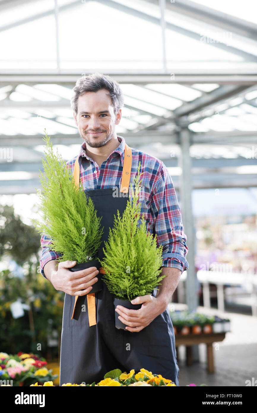 gardener holding two potted plants in a garden center Stock Photo - Alamy