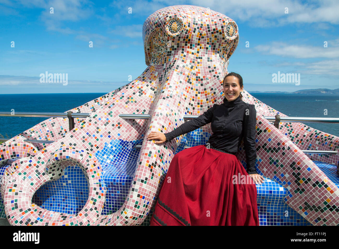Turistella tour guide in traditional dress sitting on a giant mosaic octopus sculpture, Corunna La Coruna, Galicia, Spain Stock Photo
