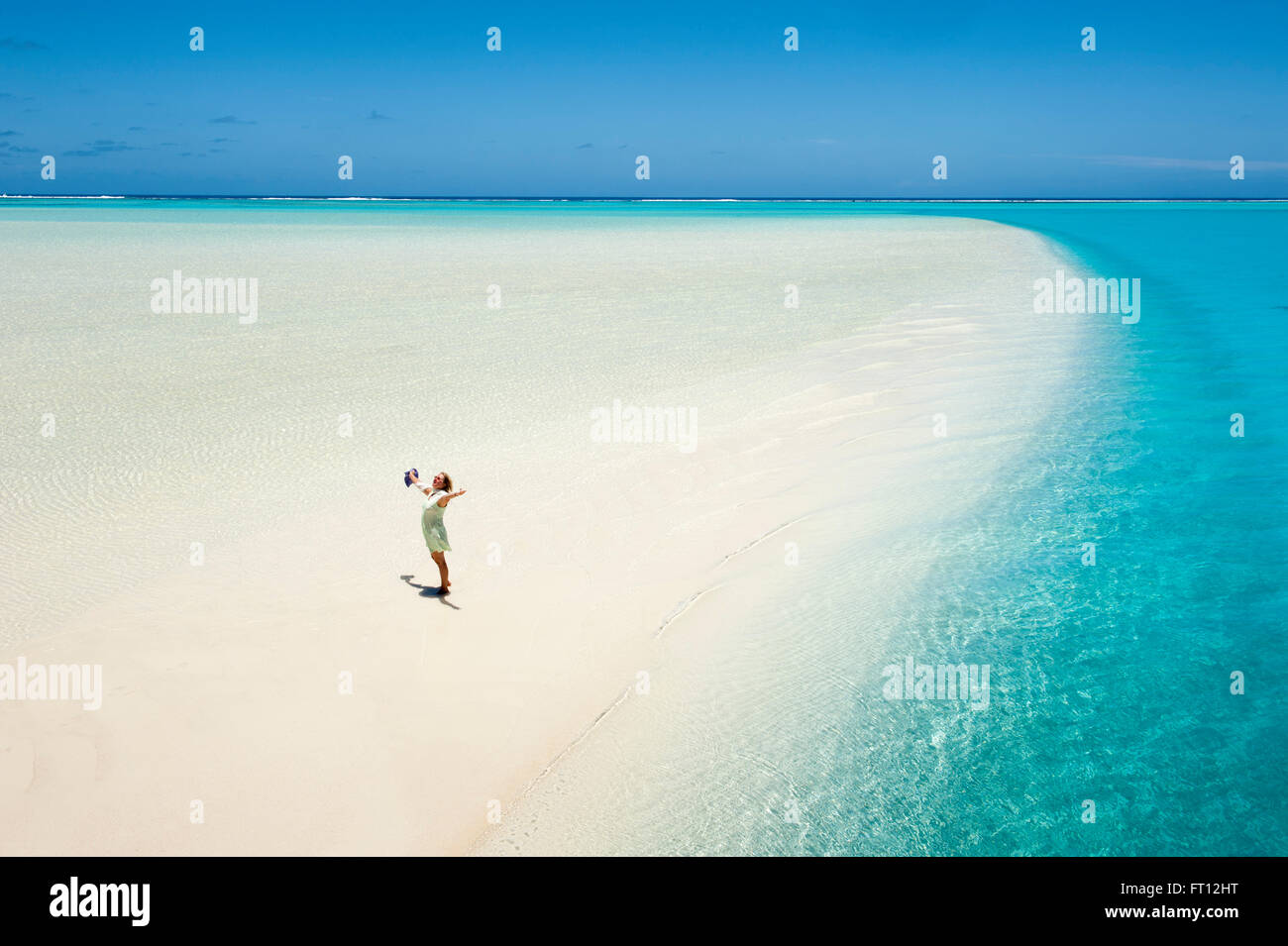 A woman opening her arms in delight on a sand bank at One Foot Island in Aitutaki Lagoon, Aitutaki, Cook Islands, South Pacific Stock Photo