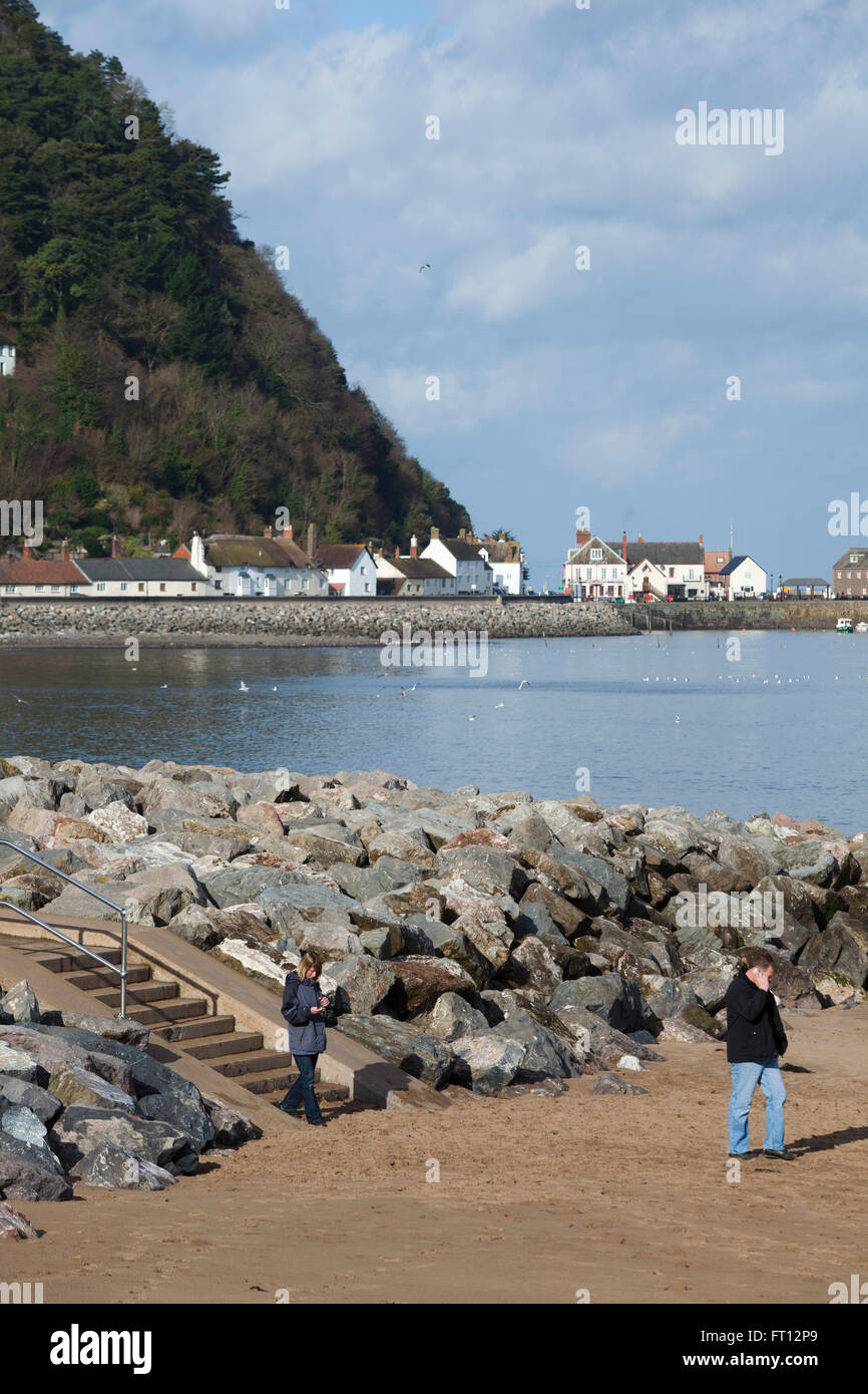 A couple walk on the town beach at Minehead in the the county of Somerset in the Uk with the harbour in the background Stock Photo