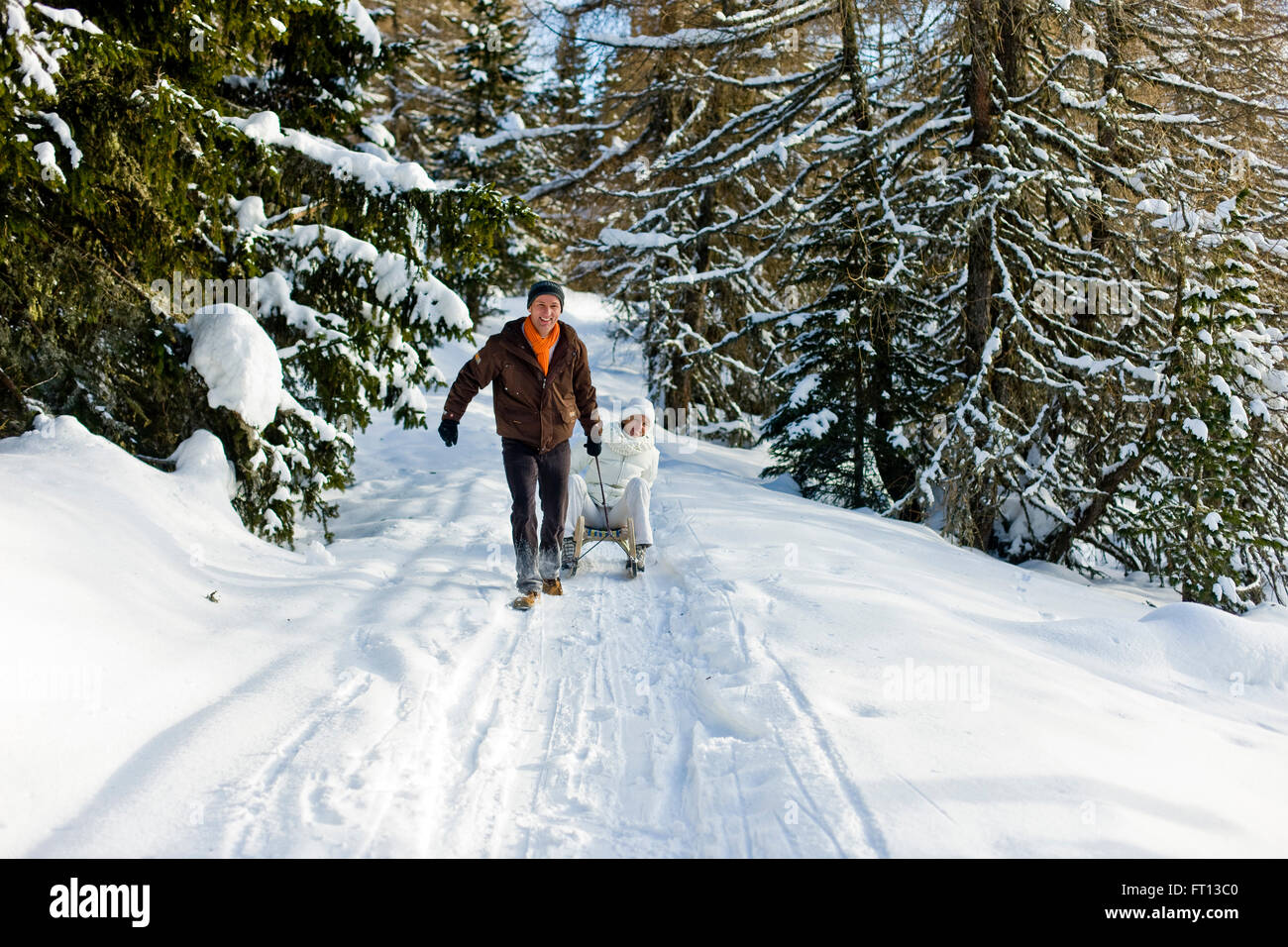 Man pulling a woman sitting on a sledge, Muehlen, Styria, Austria Stock Photo