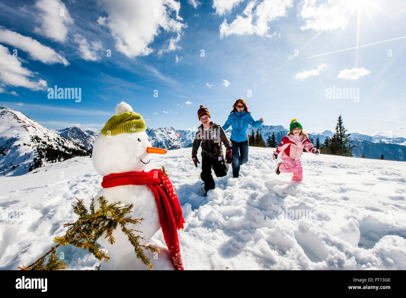 Mother and two children in snow near a snowman, Planai, Schladming, Styria, Austria Stock Photo
