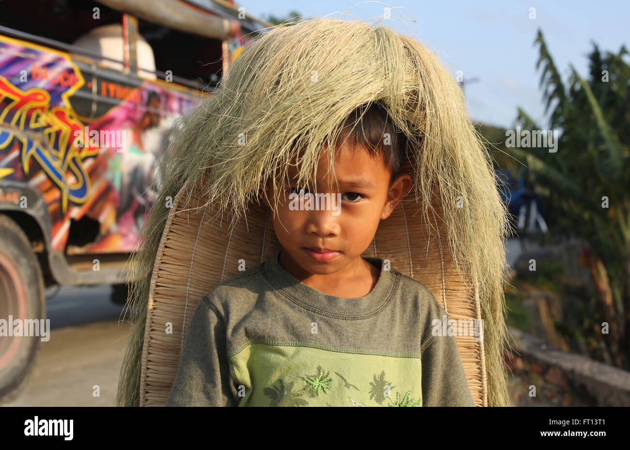 Boy wearing traditional straw wig with a jeepney in the background, Batan Island, Batanes, Philippines, Asia Stock Photo
