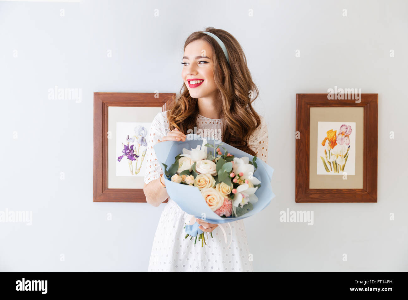 Beautiful cheerful young woman with bouquet of flowers standing and ...