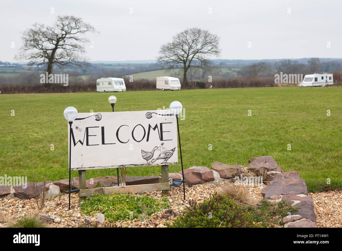 A campsite on a devon farm with caravans and a large hand painted Welcome sign in the foreground. Stock Photo