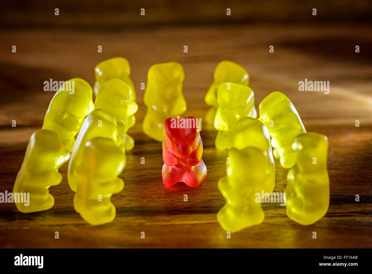 red gummy bear surrounded by yellow gummy bears Stock Photo
