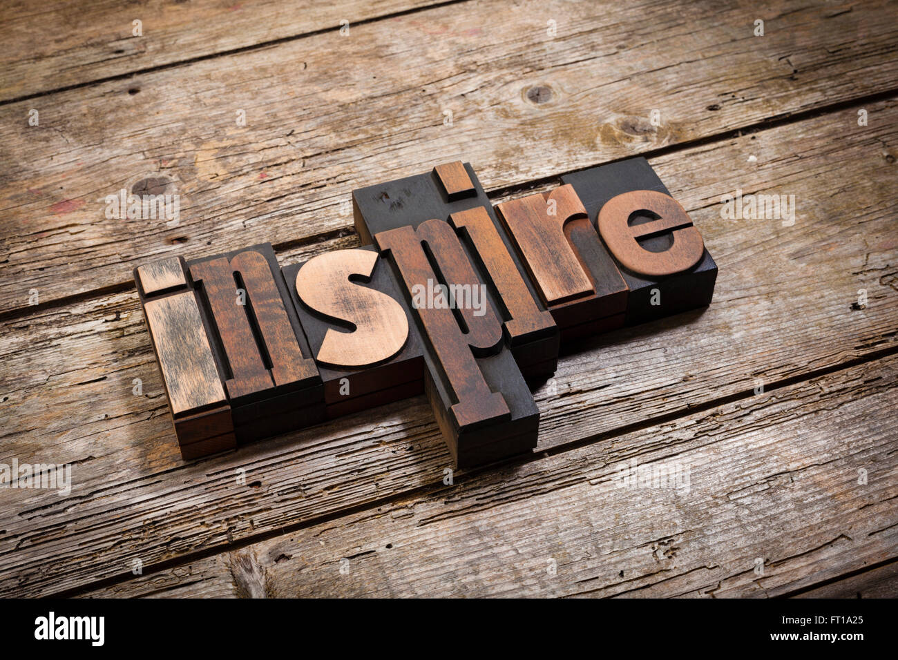 Inspire, word written with vintage letterpress printing blocks on rustic wooden background, angled view Stock Photo