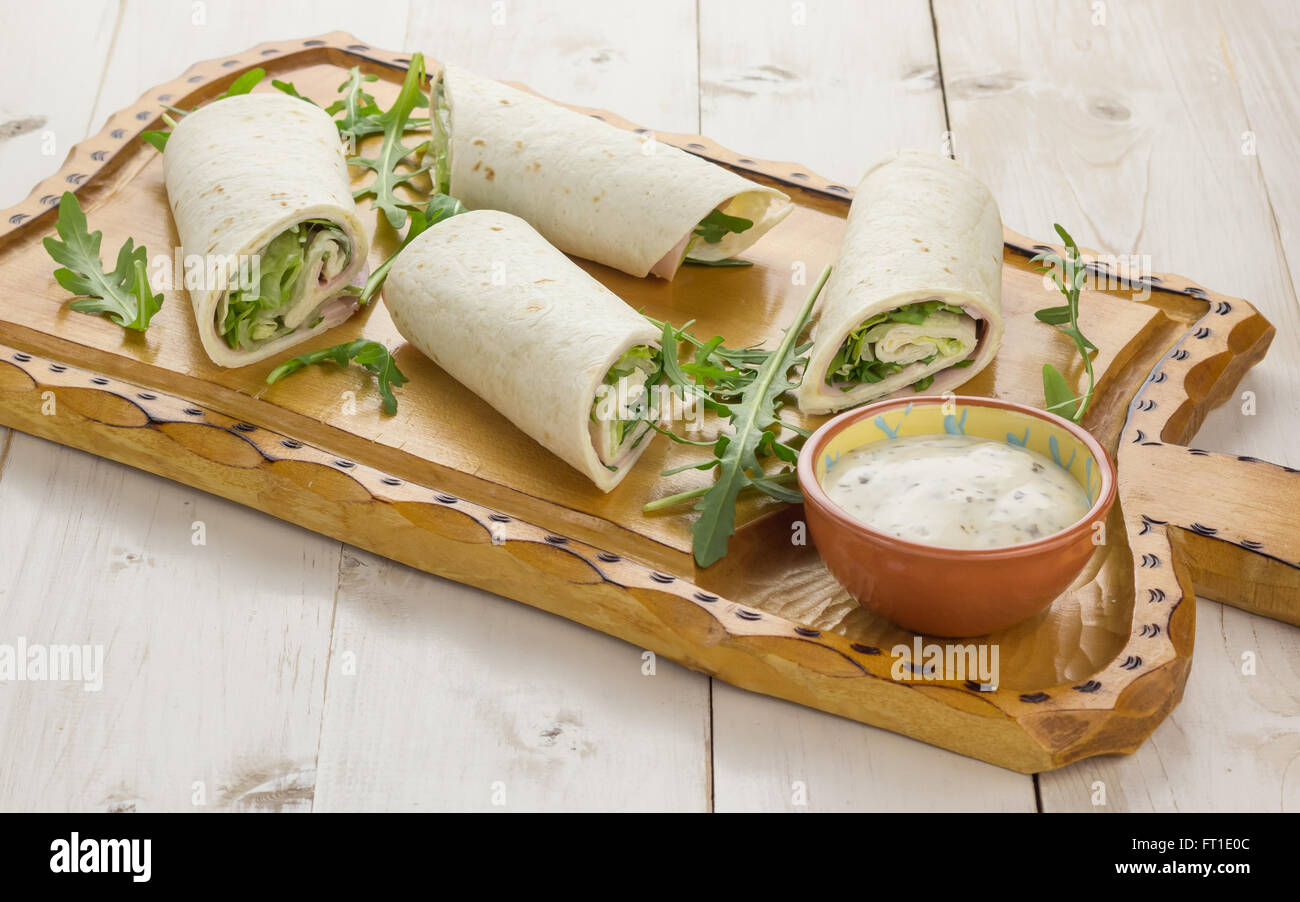 Cold wraps filled with ham and lettuce. Served with yogurt sauce on a