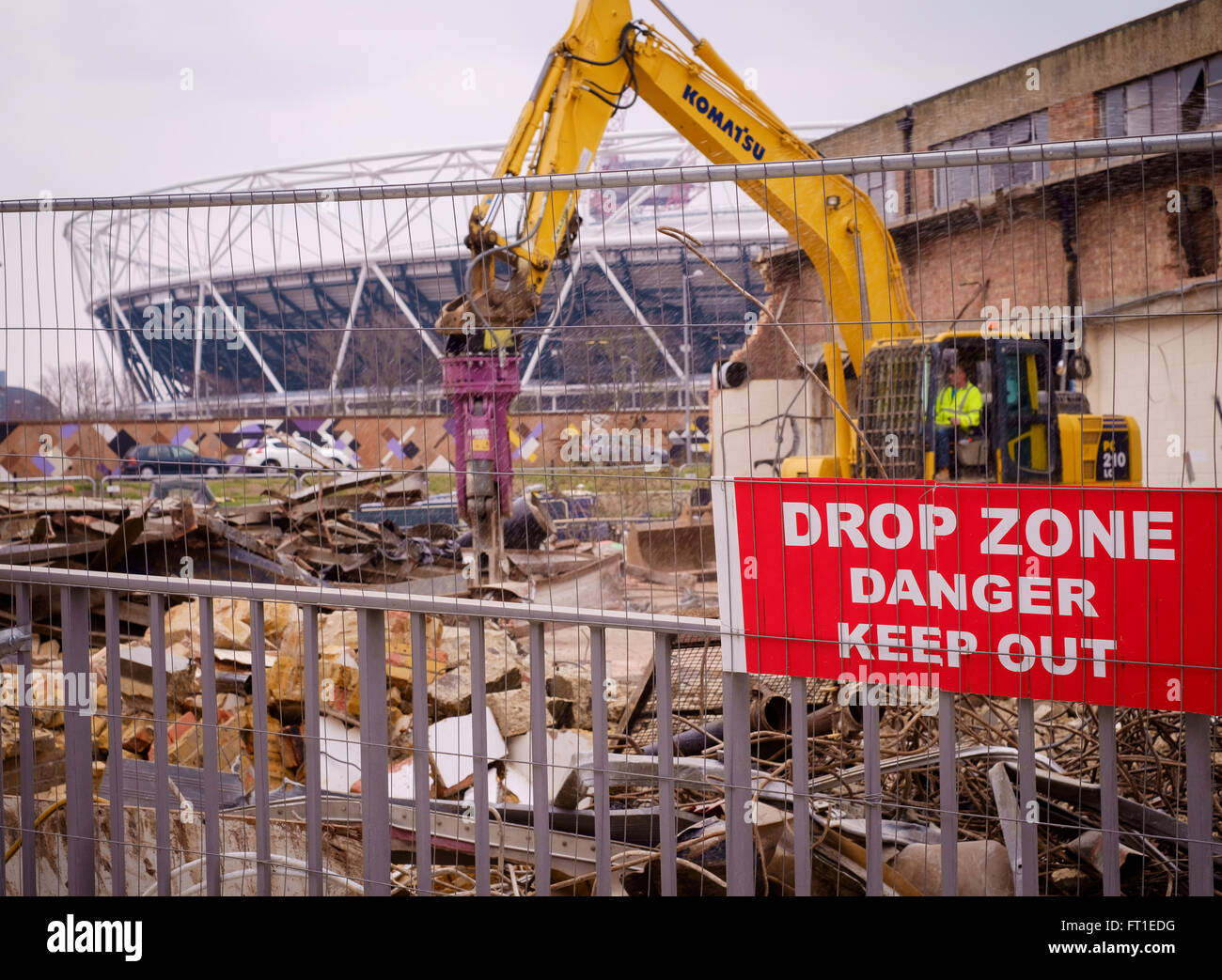 Bulldozers demolish warehouses for redevelopment in East London, in the shadow of the Olympic  Stadium, now the home of West Ham Stock Photo