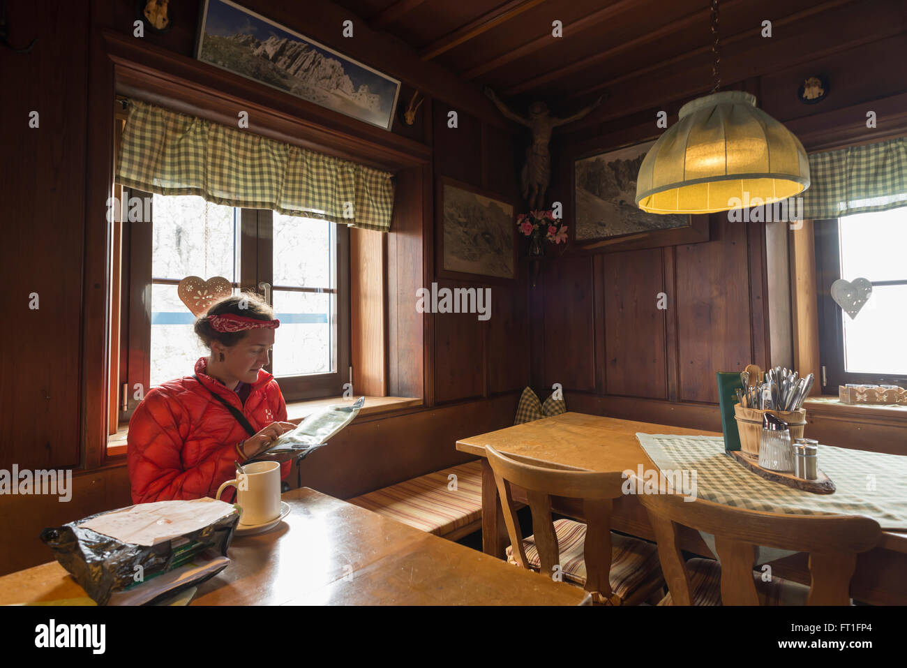 Woman studying hiking map in the traditional alpine style guest room of the Meiler hut at the Wetterstein mountains,Bavaria Stock Photo