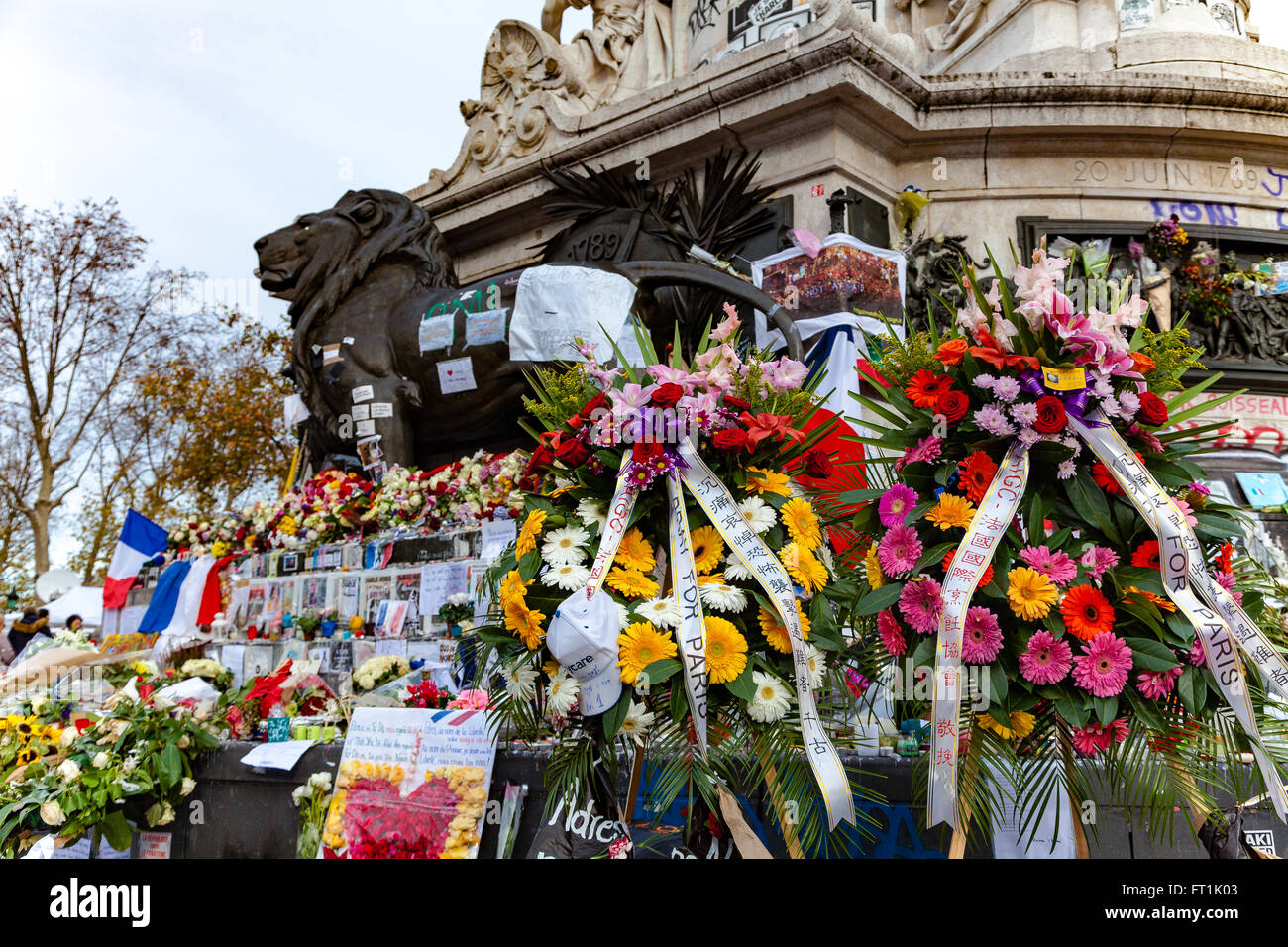Flowers and flags paying tribute to terrorism victims in Paris France Stock Photo