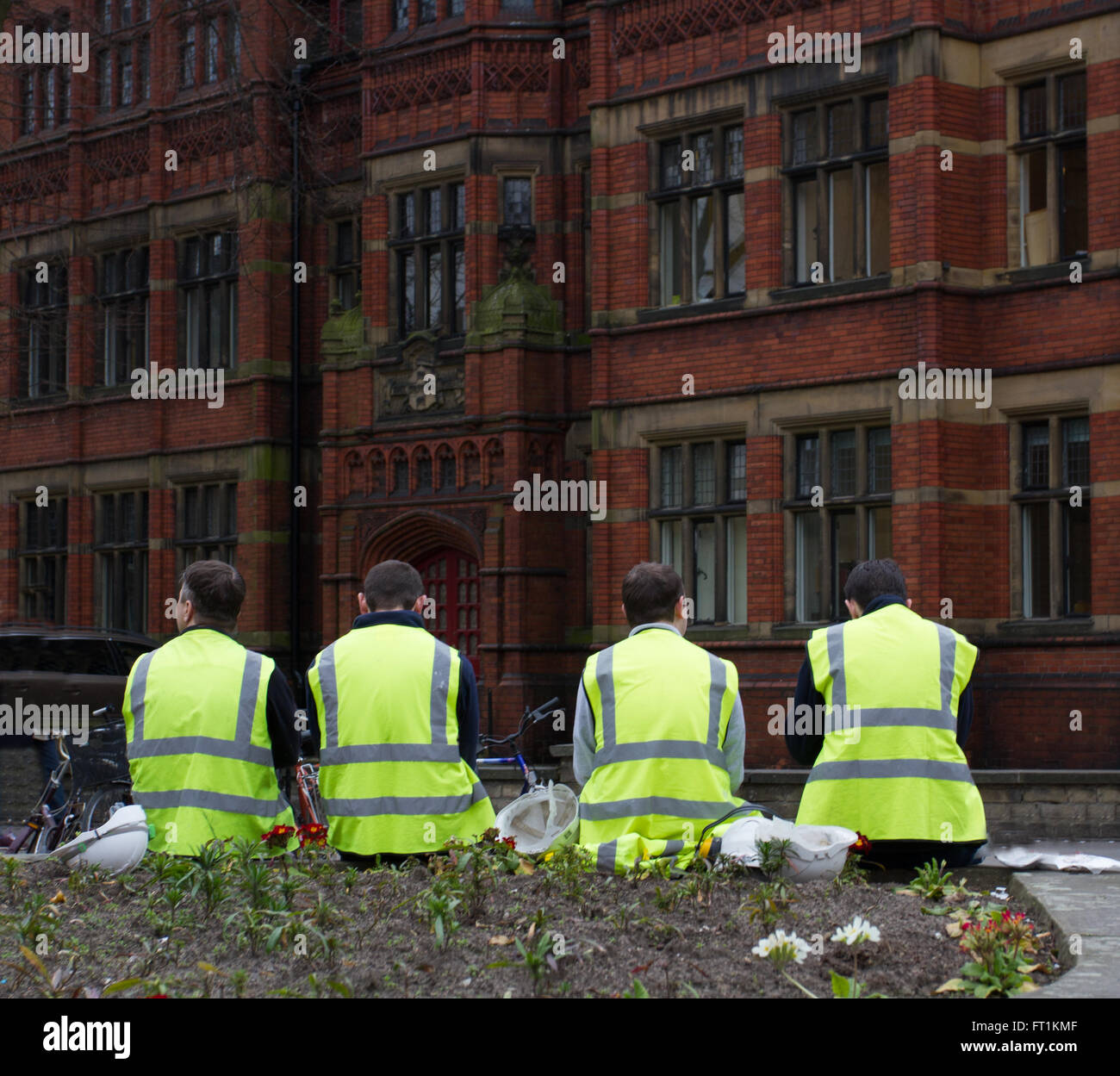 Four construction workers in high visibility clothing sitting on the streets of York during a break in work. Stock Photo