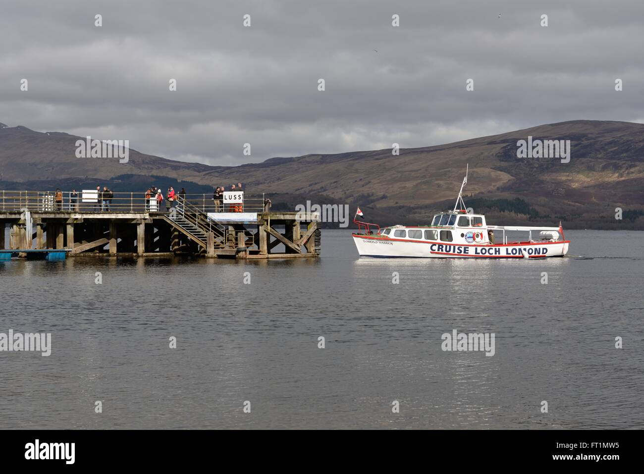 A small cruise boat approaching Luss pier on Loch Lomond, Argyll & Bute, Scotland, UK Stock Photo