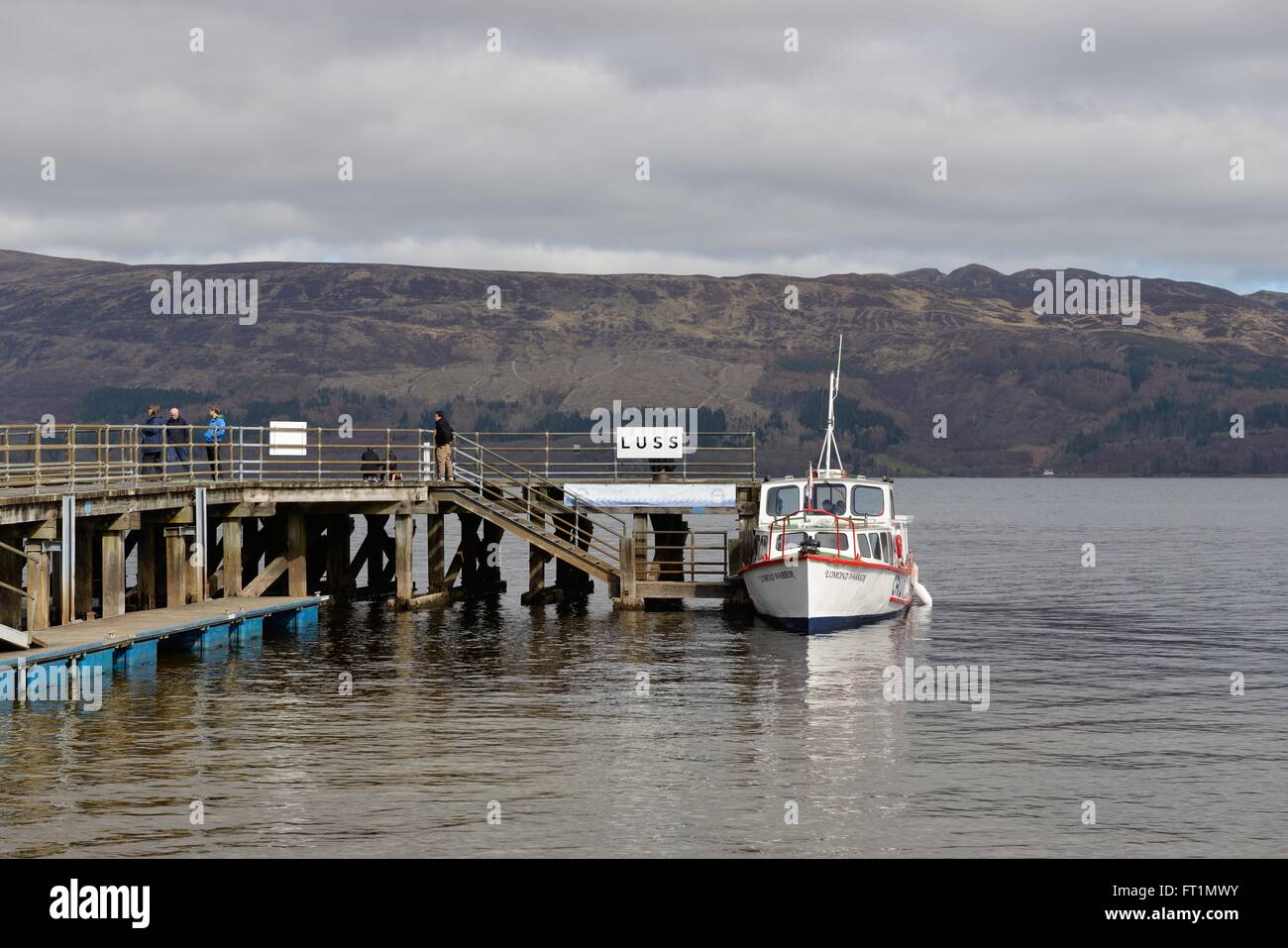 A small cruise boat alongside Luss pier on Loch Lomond, Argyll & Bute, Scotland, UK Stock Photo