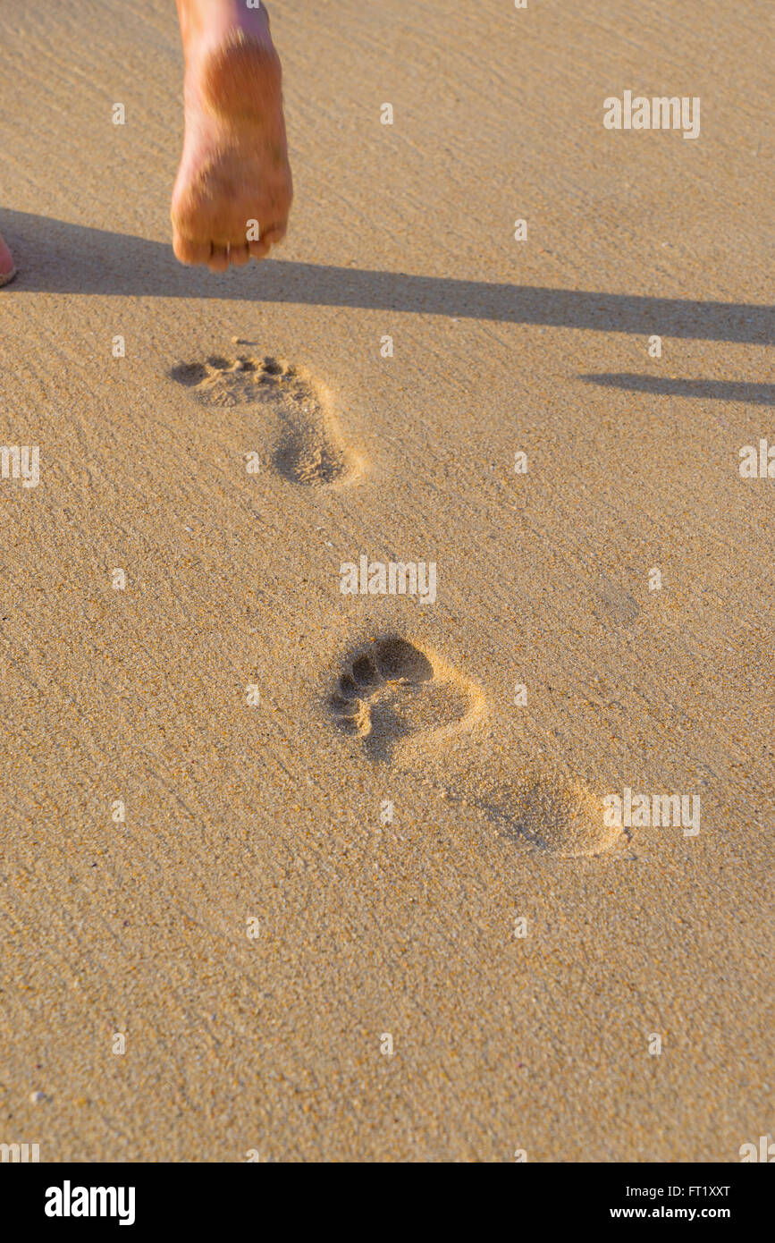 Beach travel - woman walking on sand beach leaving footprints in the ...