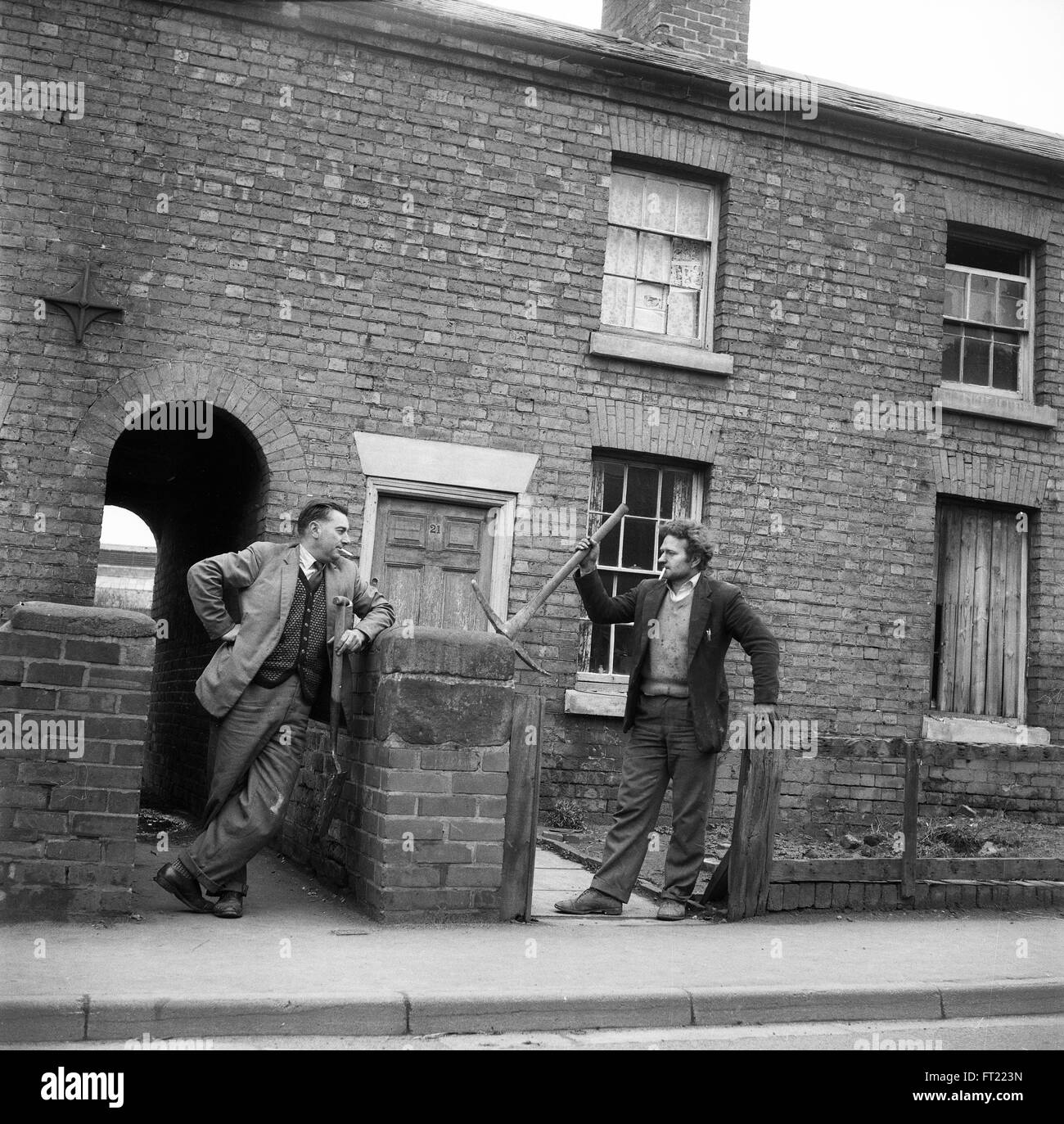 Working men neighbours talking outside condemned terraced homes in Britain 1962 1960s just before they were demolished. Stock Photo