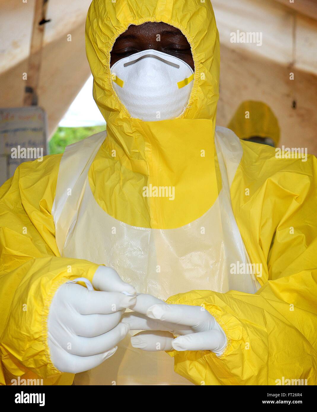 A medical team member puts on personal protective gear at the Ebola clinic at the Wilberforce Barracks November 7, 2014 in Freetown, Sierra Leone. The Ebola clinic is a joint operation with the British armed forces and Republic of Sierra Leone Armed Forces. Stock Photo
