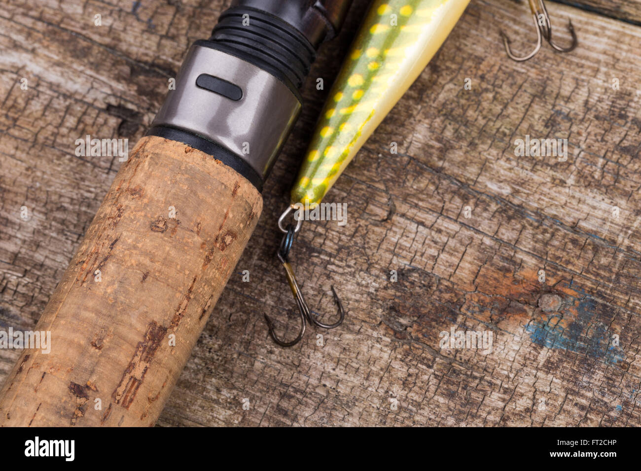 closeup cork handle of fishing rod with lure on wooden board