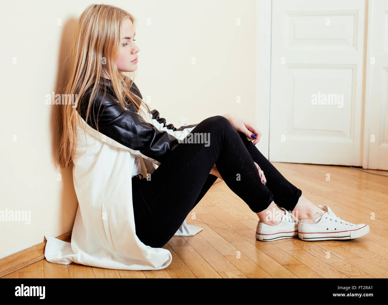 young pretty teenage blond girl sitting on floor at home despair sad ...