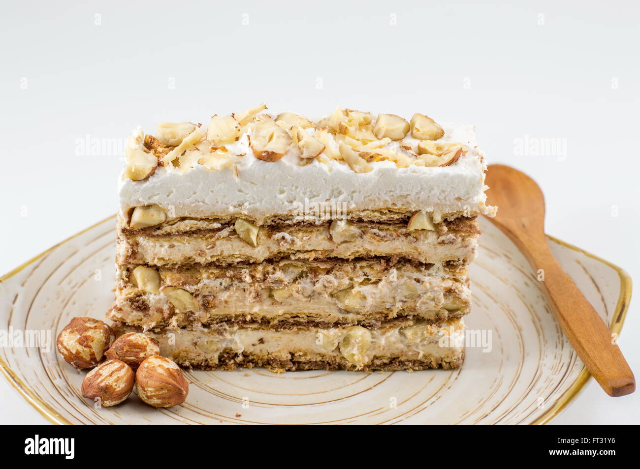 Hazelnut cake slice on a plate aginst white background Stock Photo