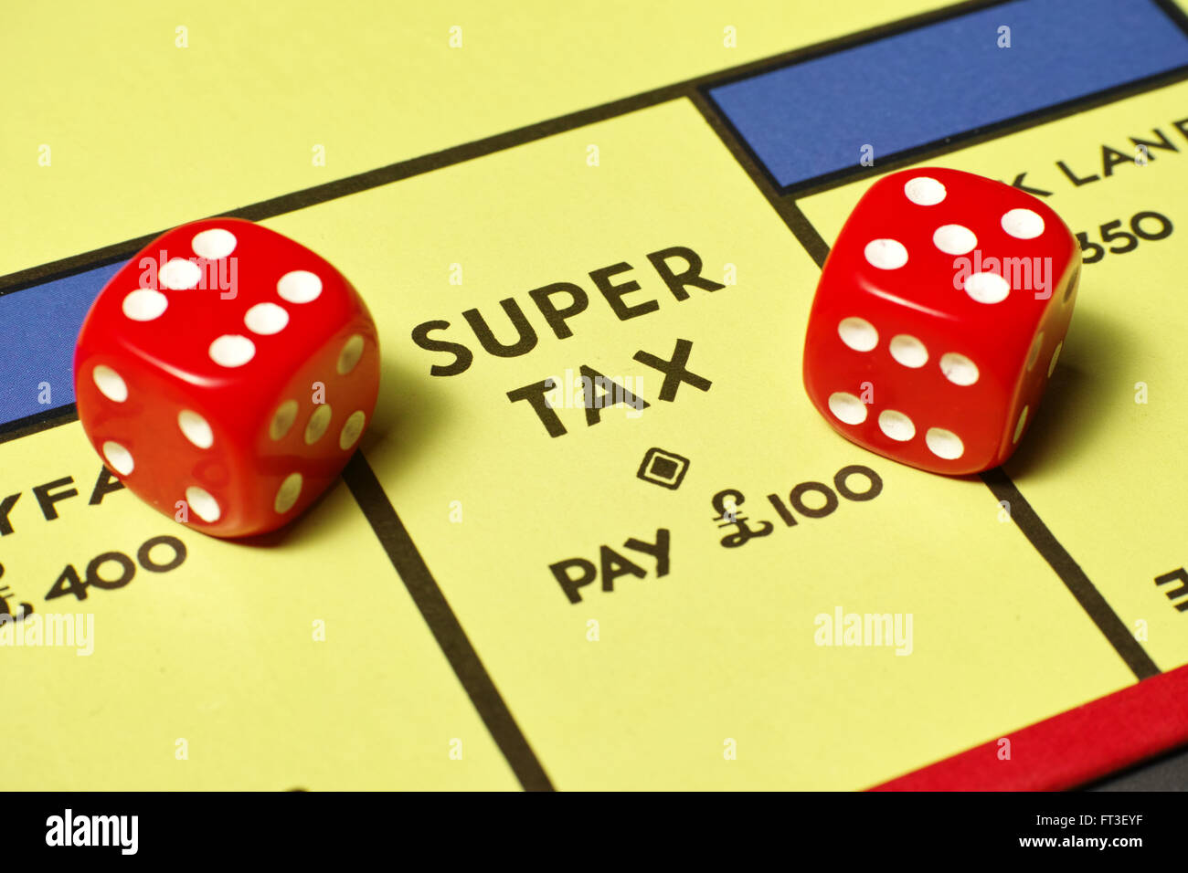 Super Tax demand on Monopoly board with red dice Stock Photo