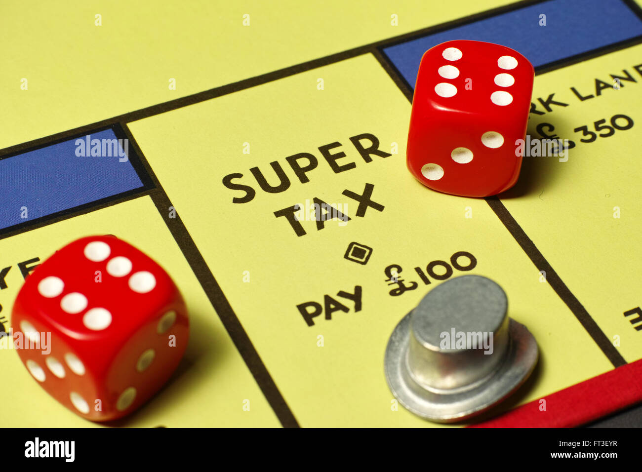 Top hat on Super Tax position on Monopoly board with red dice Stock Photo -  Alamy