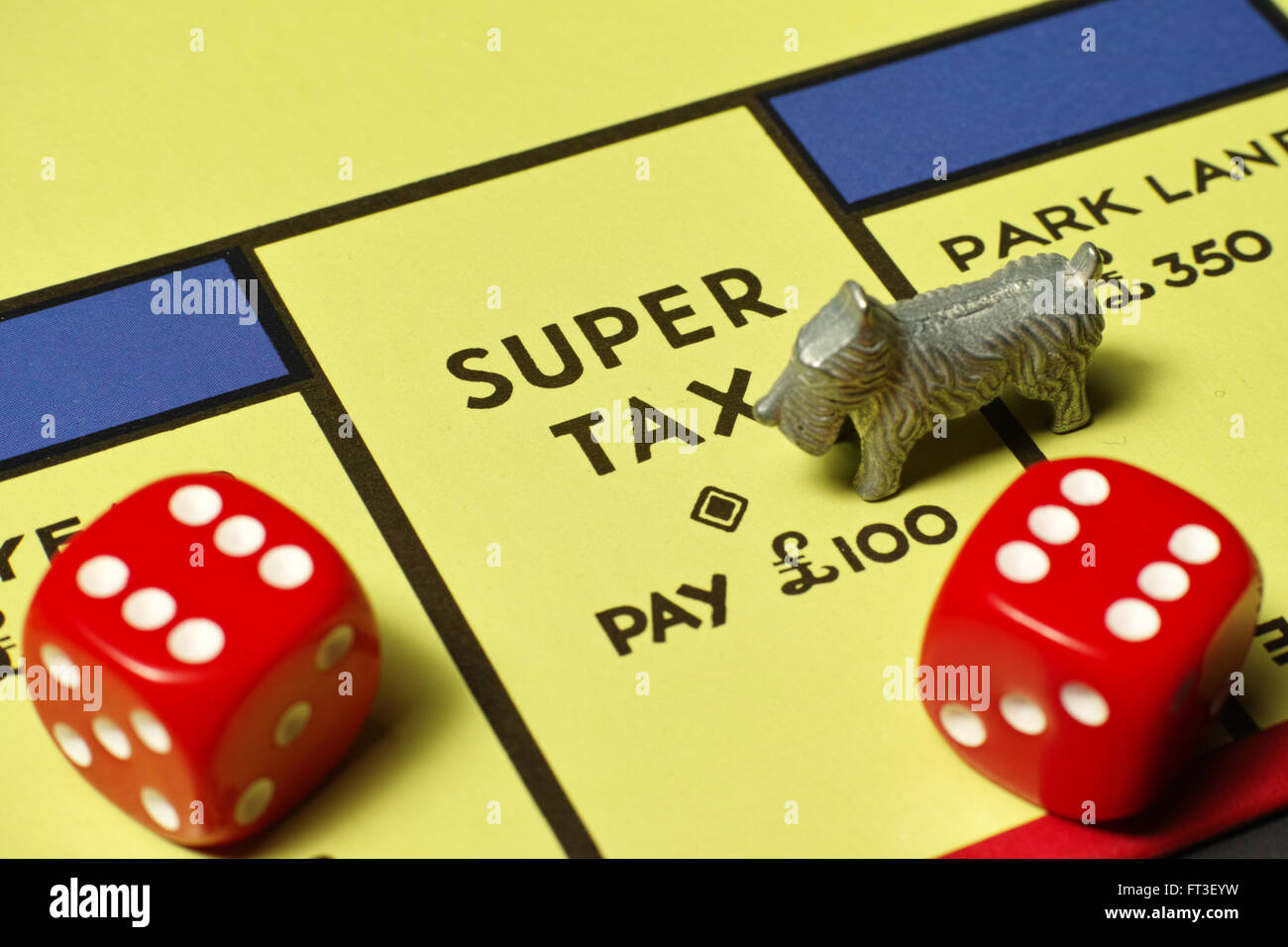 Dog on Super Tax position on Monopoly board with red dice Stock Photo