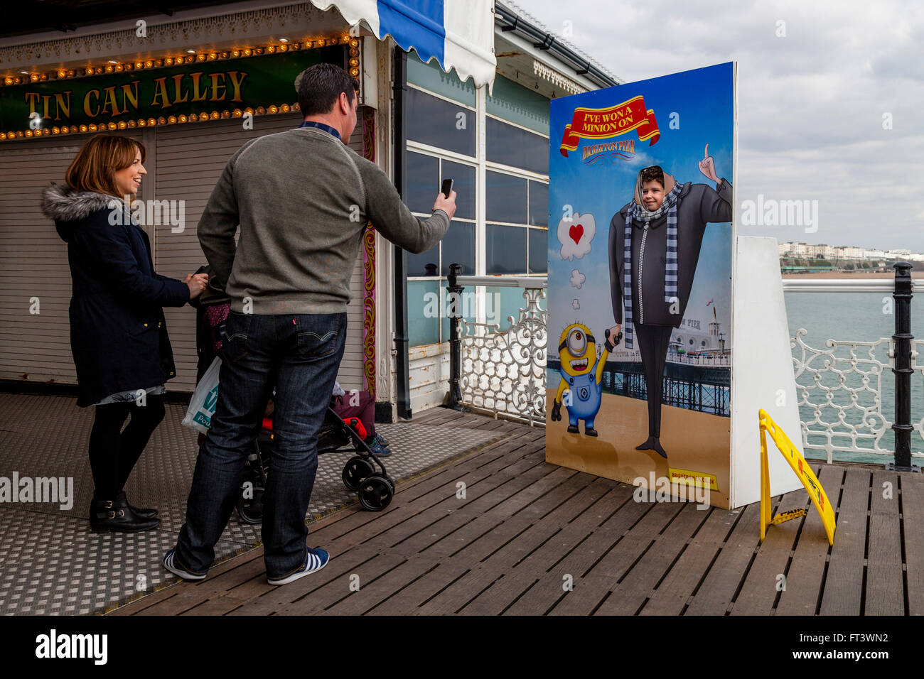 A Family Pose For Photos At One Of The Face Cut Out Photographic Boards, Brighton Pier, Sussex, UK Stock Photo