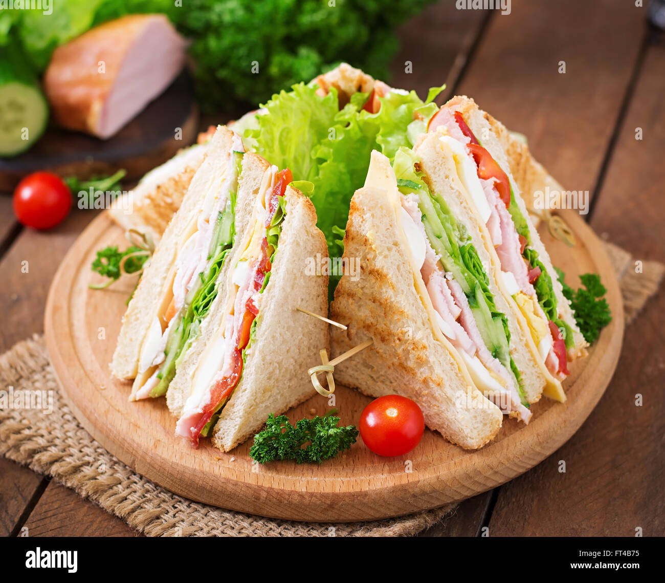 Club sandwich with cheese, cucumber, tomato, ham and eggs. Stock Photo