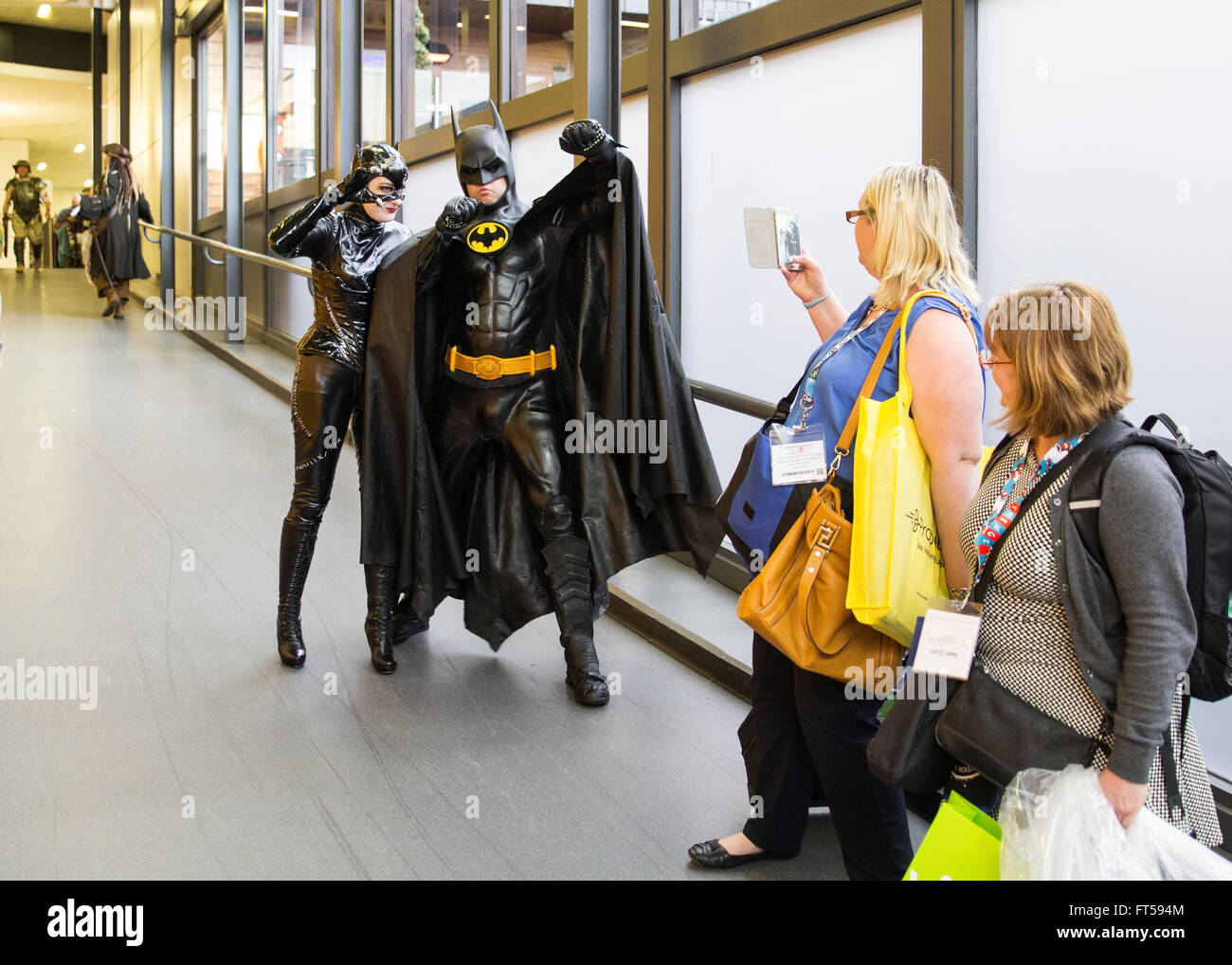 Batman and Catwoman posing for a woman to photograph them on her phone Stock Photo