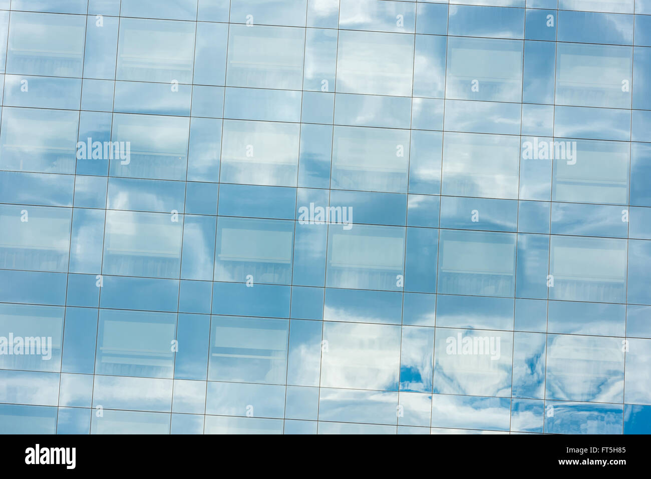 blue sky and clouds reflected in windows of modern office building ...