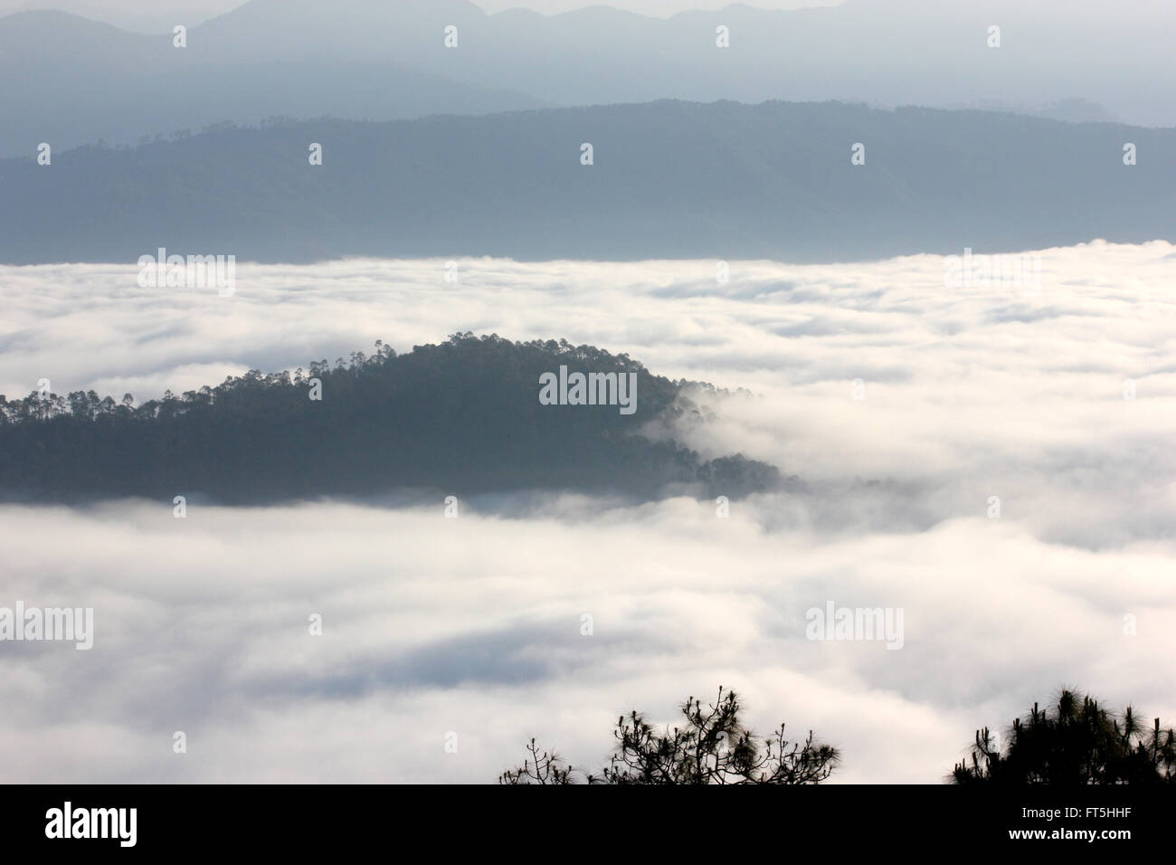 Low lying clouds in Himalayas viewed from Nainital, Uttarakhand, India with distant mountain slopes with forests Stock Photo