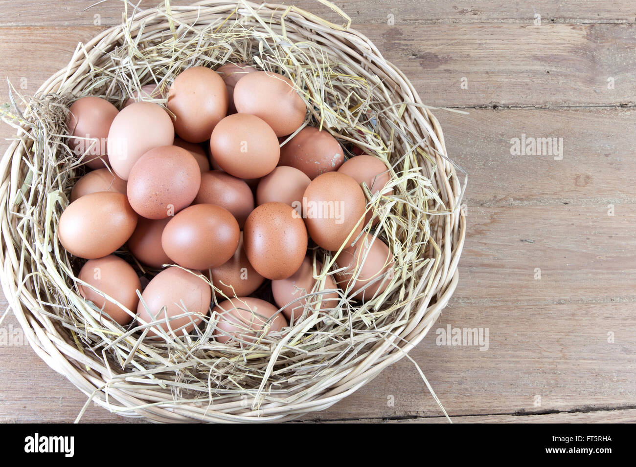 eggs in a rattan basket with straw secondary on wood background Stock Photo