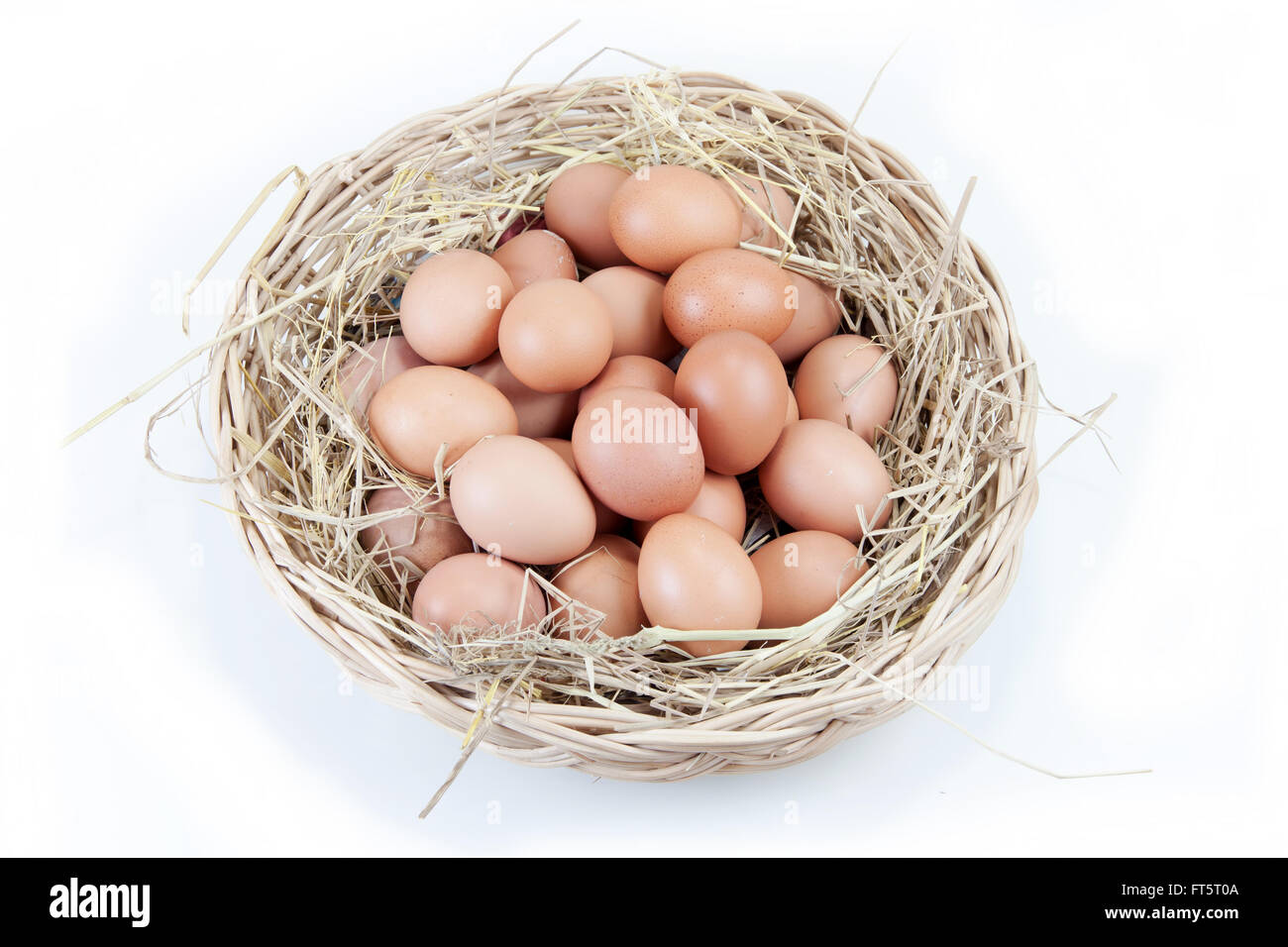 eggs in a rattan basket with straw secondary on white background Stock Photo