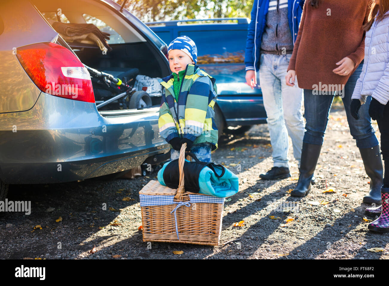 Little boy trying to pick up picnic basket by family and car in countryside Stock Photo Alamy
